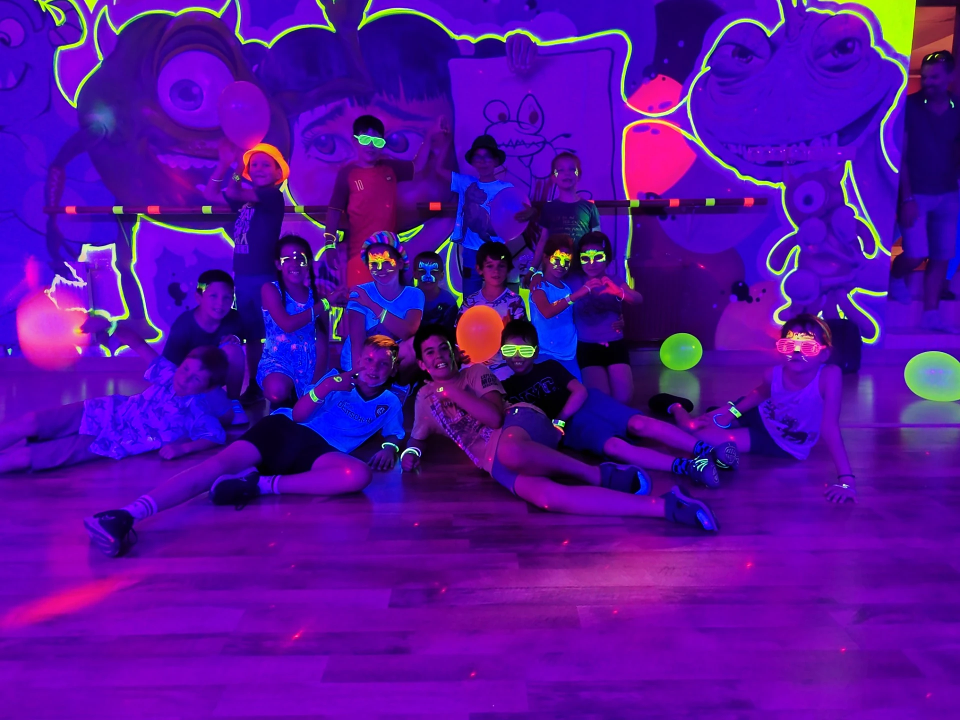 Közös szülinapi ünneplés és baráti csapatkép a neon graffiti falnál